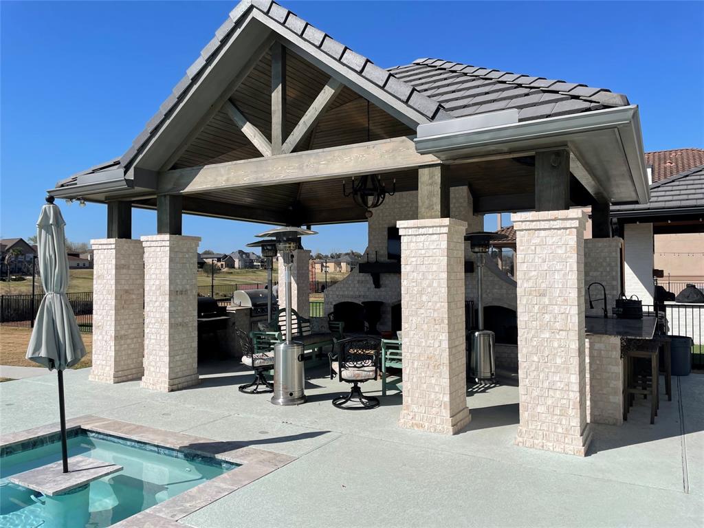 Huge outdoor living area with large fireplace, cooking area, and island