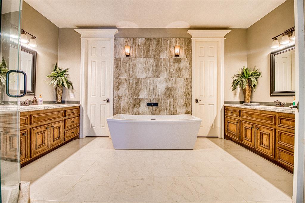 [Primary bath] Granite primary bath featuring custom cabinetry, a glass and granite shower and matching sink vanities.