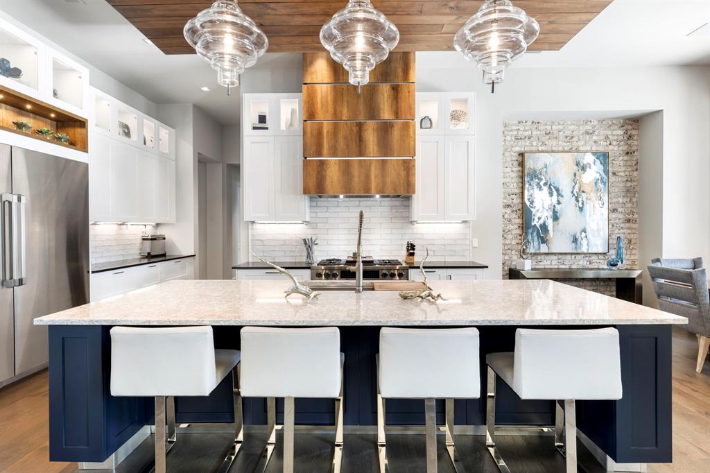 Island with bar seating, stainless steel kickplates, clear glass pendant lights, and soft close cabinets and drawers that can be found throughout the entire home.