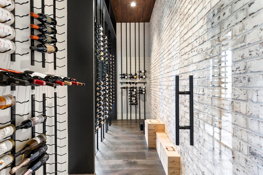 The wine gallery features floating wall racks with a brick backdrop.
