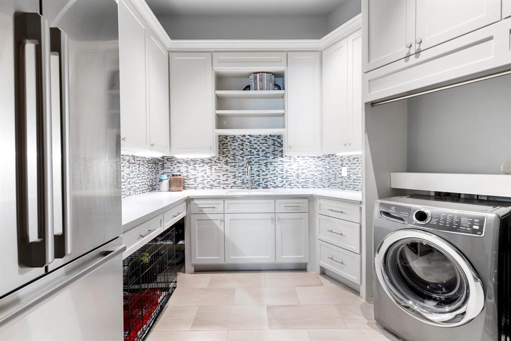 Laundry / Utility Room: highlights a silver mist tile backsplash complimenting generous storage cabinets and works space. Plenty of room for full washer/dryer and second fridge.