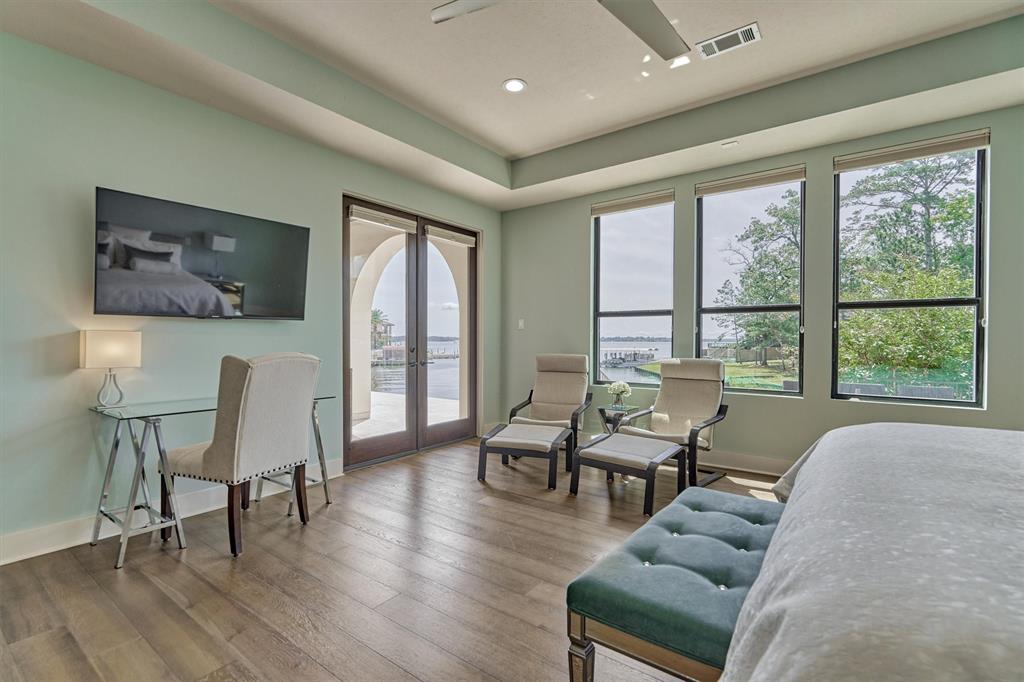 PRIMARY BEDROOM - Downstairs owner’s suite w/lake views, outdoor access, recessed ceiling, strategically placed overhead recessed reading lights & 2-way remote-controlled Heatalator gas fireplace