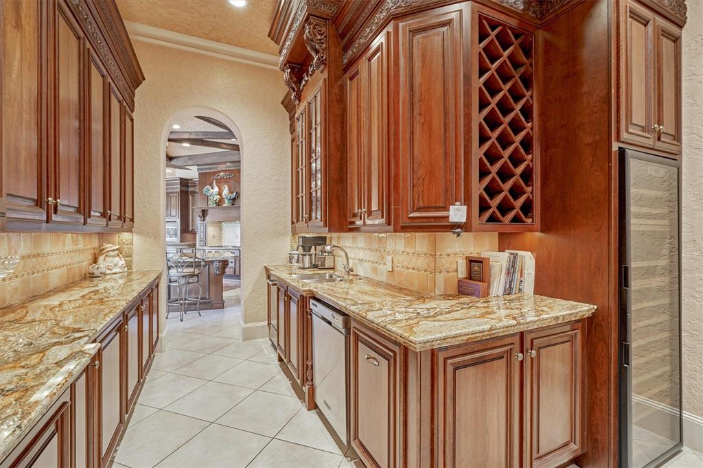 BUTLER WALKTHROUGH PANTRY - Beautiful custom cabinetry and granite carry into the oversized butler's pantry. Lighted display cabinet with glass shelves. Serving station with extra dishwasher and ice maker. Oversized wine refrigerator and tons of storage.