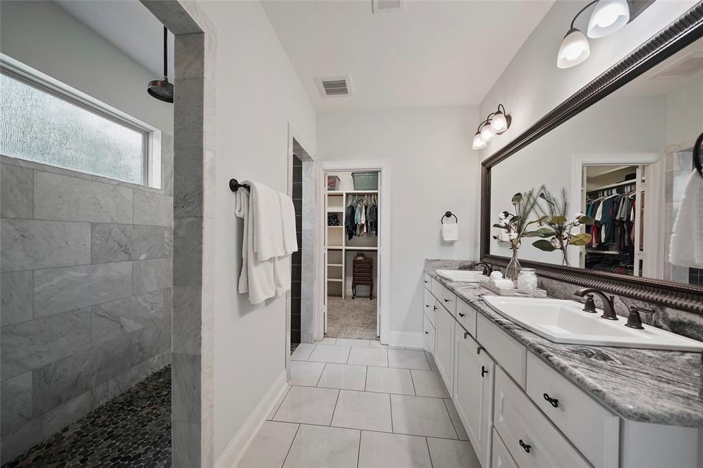 Primary bathroom with dual sinks, walk-in closet and walk through shower.
