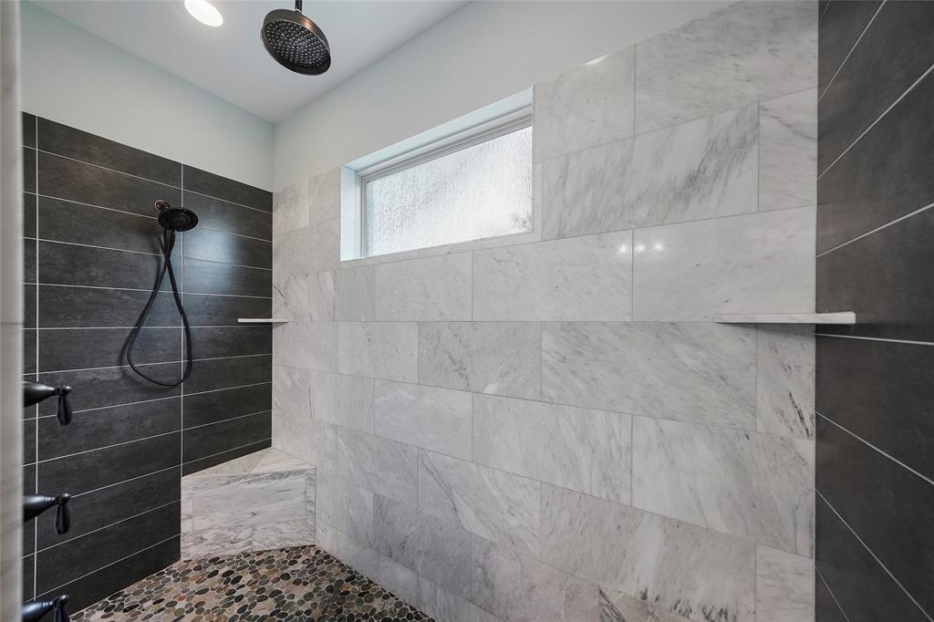 Huge shower with pebble rock flooring and 3 shower heads.