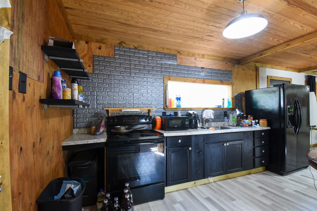 Kitchen area includes an electric range (approx. 4yrs old), laminate countertop, large picture window above the sink overlooking the property.